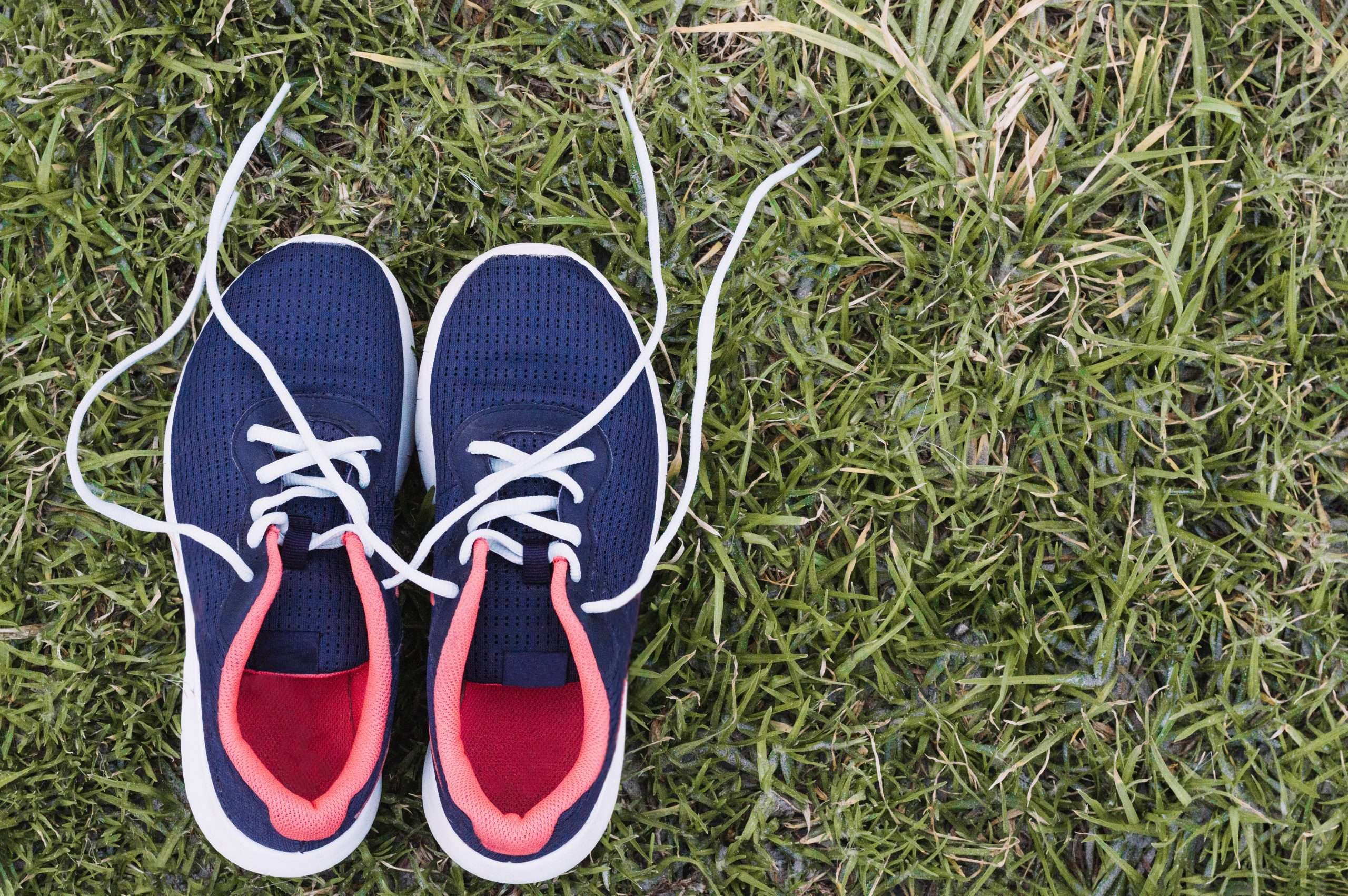 Pair of supportive athletic shoes on grass used to illustrate proper footwear for reducing heel pain from standing all day