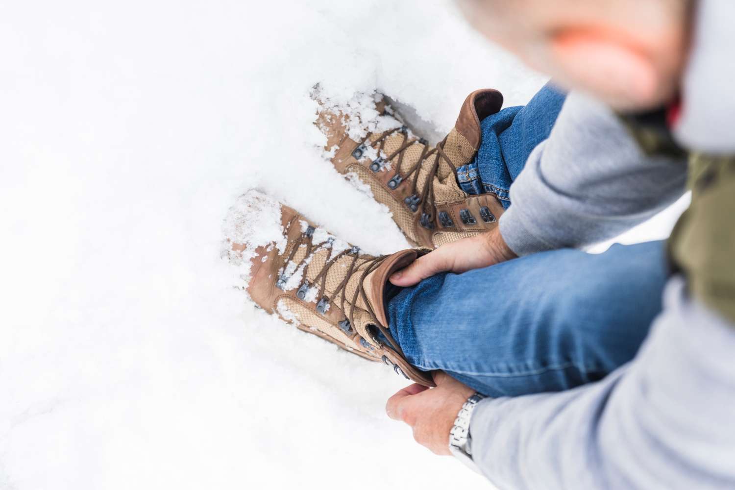 Winter Boots Being Adjusted in Deep Snow for Safe Walking Close up of a person sitting in the snow and tightening winter boots, showing proper footwear for preventing slips on ice and snowy conditions.