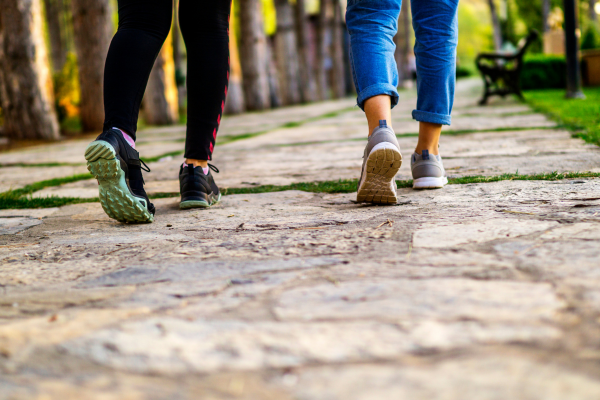 Two people walking comfortably on a stone path in athletic footwear, illustrating the improved mobility and pain-free daily activity outcomes achieved with custom orthotic treatment at Foot & Ankle Centers of New Jersey
